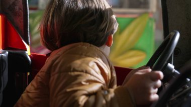 Çocuk elleri direksiyon tutarken lunaparktaki atlıkarıncada sürüyormuş gibi yapıyor.