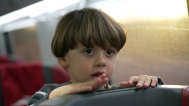 Tren koltuğunda duran çocuk yüksek hızlı trenin içinde seyahat ediyor. Tatilde seyahat eden bir çocuğun yakın plan yüzü.