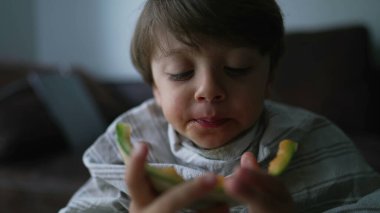 Çocuk kavun meyvesi bitiriyor. Küçük çocuk meyveli tatlı yiyor. Çocuk sağlıklı besleniyor.