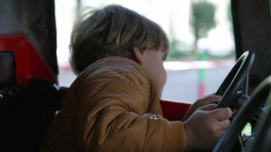 Çocuk elleri direksiyon tutarken lunaparktaki atlıkarıncada sürüyormuş gibi yapıyor.