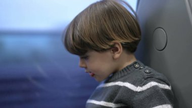 Trenle seyahat eden küçük bir çocuk manzarayla pencereye bakıyor. Çocuk hızlı trenle seyahat ediyor.