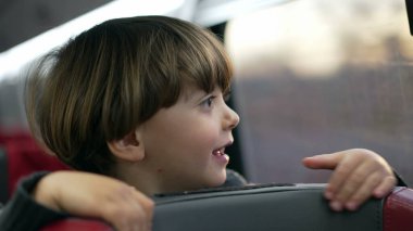 Tren koltuğunda duran çocuk yüksek hızlı trenin içinde seyahat ediyor. Tatilde seyahat eden bir çocuğun yakın plan yüzü.