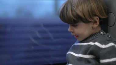 Trenle seyahat eden küçük bir çocuk manzarayla pencereye bakıyor. Çocuk hızlı trenle seyahat ediyor.