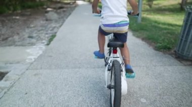 Parkta çocuk bisikleti sürüyor. Bisiklete binen aktif bir genç dışarıda kask takıyor.