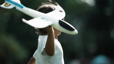 Çocuk uçak planörünü havaya fırlatıyor. Uçuş konsepti. Çocuk pilot dışarıda oynuyor.