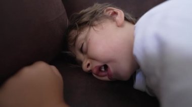 Kanepede uyuyan küçük bir çocuk. Yorgun çocuk, yüzünü kapat, esne, uyu.
