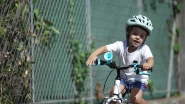 Mutlu çocuk kask takarak bisiklet sürüyor. Bisikletli çocuk kaldırımda bisiklet sürüyor.