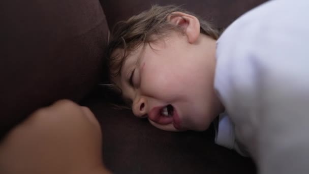 ソファで寝ている男の子が一人いる 疲れた子供顔を閉じてあくびが眠りに落ちる — ストック動画