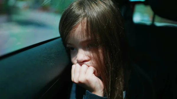 Portrait of a bored sleepy child feeling bore and sadness. Sad little girl closeup face traveling by car leaning on car window backseat