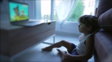 Çocuk evde çizgi film izliyor. İnternette eğlence medyası içeriği tarafından hipnotize edilen küçük bir çocuk.