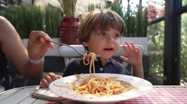 Çocuk yemeği reddediyor. Çocuk öğle yemeği için restorandaki masada kırmızı soslu spagetti yemek istemiyor.