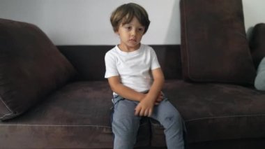 Evde boş boş oturan canı sıkkın bir çocuk. Düşünceli bir ifadeyle sıkılmış genç bir çocuk.
