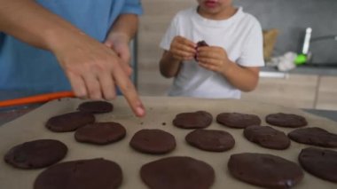 Çocuk ve anne ev mutfağında kurabiye hazırlıyor. Bir sürü çikolatalı tatlı. Çocuk ailesiyle yemek pişiriyor.