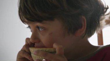 Kavun meyvesi yiyen bir çocuğun portresi. Genç çocuğun yüzünü kapatın ve kahvaltı masasında sağlıklı yemekler yiyin.