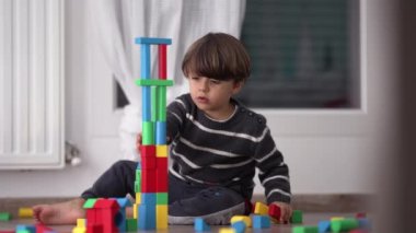 Renkli blokları olan bir çocuk kulesi. Yatak odasında yerde oynayan küçük bir çocuk. Gizli yaşam tarzı çocukluk yaratıcı gelişimi