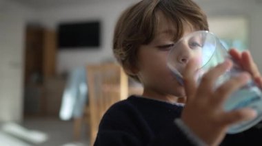 Mutlu çocuk büyük plastik bardakta su içiyor. Su içen küçük bir çocuk.