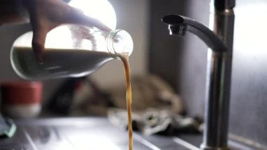 Eski sütü mutfak lavabosuna döküyorum. Bozuk yiyecekleri atarken.