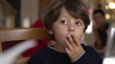 Lokanta yemeğinde tatlı yiyen düşünceli çocuk.
