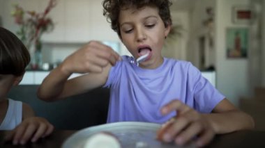 Genç çocuk kahvaltı masasında oturmuş yumurta yiyor. Çocuk sağlıklı abur cubur yiyor.