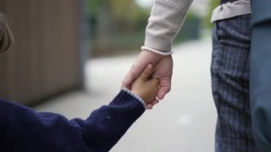 Dışarıda el ele tutuşan yakın çocuk ve anne. Ebeveyn ve çocuk el ele verip birlikte yürüyüşe çıkmışlar.