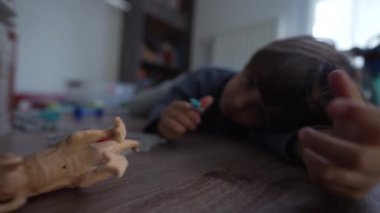 Neşeli çocuk yatak odasında oyuncaklarla oynuyor. Küçük çocuk yerde uzanıp eğleniyor.
