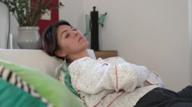 Oturma odasındaki kanepede uzanmış düşünen bir kadın. Düşünceli insan kanepede uzanıp dinleniyor.