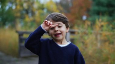 Sonbahar sezonunda parkta gezen mutlu küçük bir çocuk. Yürüyen neşeli bir çocuğun portresi.
