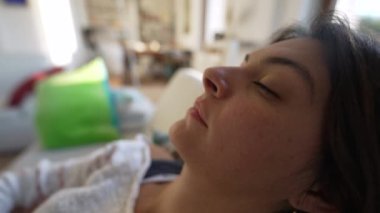 Kanepeye uzanmış gözlerini açan kadın. Şekerlemeden uyanan kişi oturma odasında yüzünü kapat.