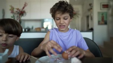 Genç çocuk haşlanmış yumurtaya tepki veriyor. Yumurta soymaya çalışan bir çocuk. Yaşam tarzı kahvaltı masası