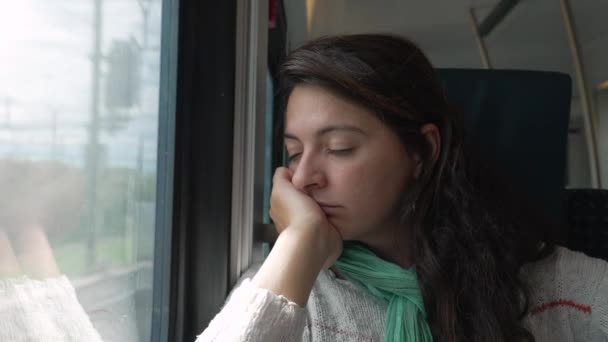 女は電車の窓からあごの中で眠っていた 高速交通による通勤 通学中の女性の乗客の昼寝 — ストック動画