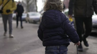 Baby toddler running in sidewalk during winter outside. Infant sprinting in city