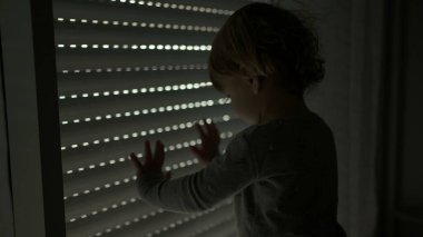 Little toddler closing automatic blinds, kid watching blinds go down