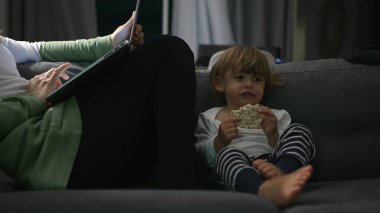 Annem geceleri dizüstü bilgisayarın önünde 2 yaşındaki bebekle kanepede oturuyor.