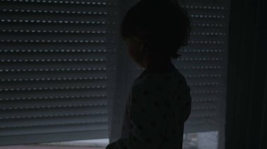 Toddler boy watching automatic blinds going down