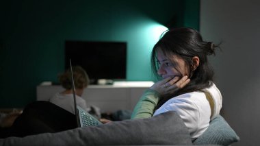 Woman using laptop computer at night in sofa