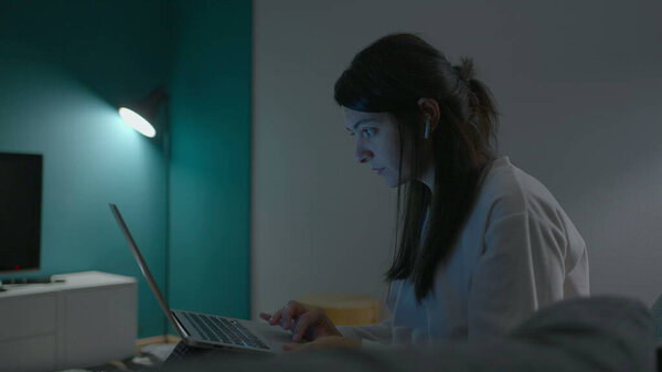Woman working or studying at night in front of laptop computer