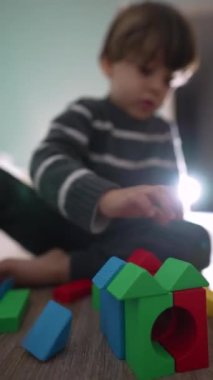 Çocuk renkli bloklarla oynuyor. Çocuk inşaat bloğuyla oynuyor. Dikey Videoda blokları olan ev yapan çocuk