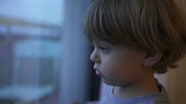 Baby toddler standing by window wanting to go out feeling bored