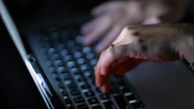 Geceleri dizüstü bilgisayarda yazan kadın elleri. Klavyede karanlıkta çalışan kişi 