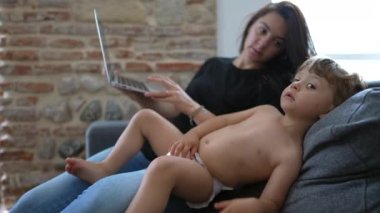 Anne bilgisayarı kullanarak evde bebek bebekle birden fazla iş yapıyor. Samimi özgün ve gerçek hayatta anne çalışıyor ve ebeveynlik yapıyor.