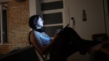 Geceleri evde çalışan bir kadın karanlıkta dizüstü bilgisayarın önünde. İnternette gezinirken kişinin yüzünde parlayan bilgisayar ekranı