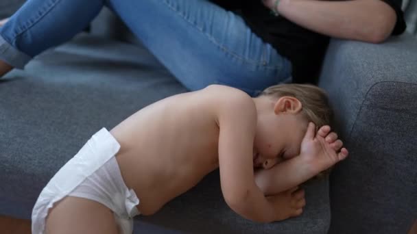 1疲れて小さな赤ちゃんを着ておむつ摩擦顔上のソファ — ストック動画