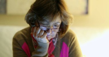 Eli çenesinde tablet ekranda oynayan yaşlı bir kadın. 60 'lı yaşlarda yaşlı bir kadın teknolojik aletleri okuyor.