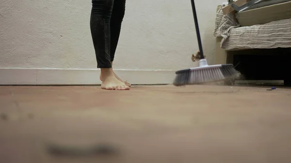 Person sweeping floor with broomstick, dusty dirty floor