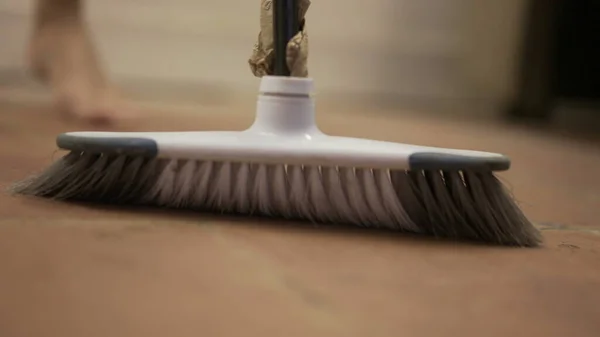 Person sweeps dirty dusty floor with broomstick