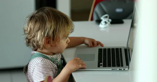 Baby boy sitting in front of laptop watching cartoon screen
