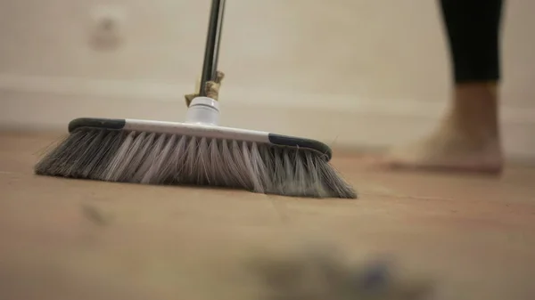 Dirty dust on floor, person sweeping floor with broomstick