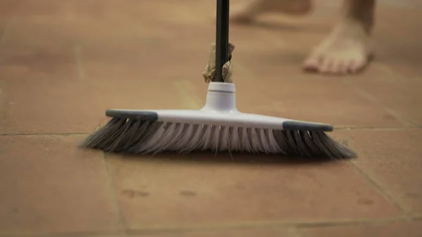 Dirty dust on floor, person sweeping floor with broomstick
