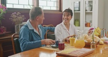 Joyful family at breakfast table. Older senior couple smiling together 