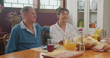 Joyful family at breakfast table. Older senior couple smiling together with daughter